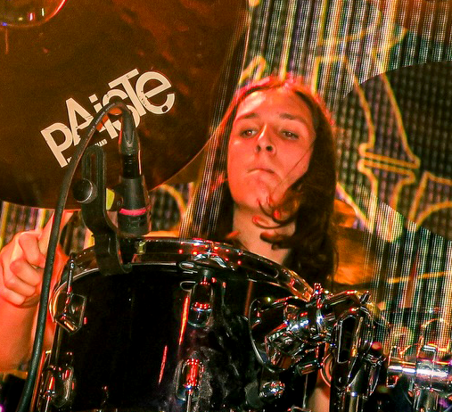 Thomas while drumming with a large Paiste cymbal in the foreground.