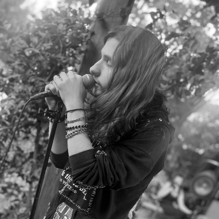 A person with long hair singing into a microphone with their eyes closed